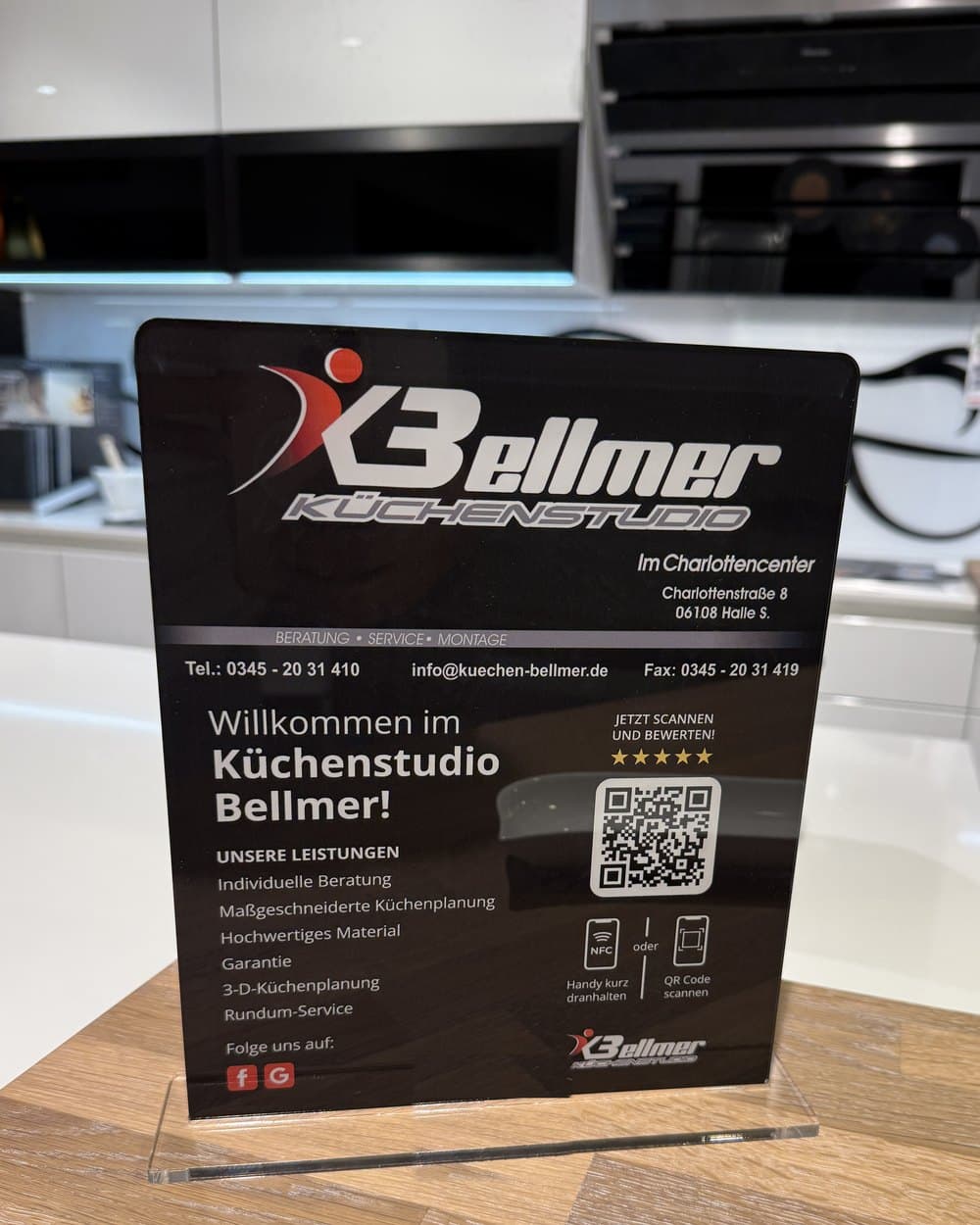 Der große Aufsteller auf dem Tresen im Küchenstudio Bellmer: „Jetzt scannen und bewerten!“ mit QR-Code, NFC und den Leistungen des Studios