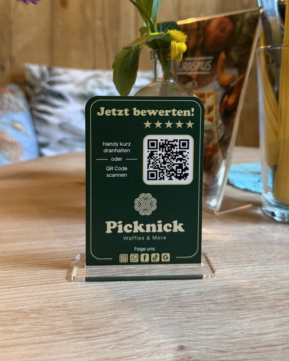 Der Aufsteller von Picknick Waffles and More auf einem Tisch im Café: „Jetzt bewerten!“ mit fünf Sternen, QR-Code und NFC