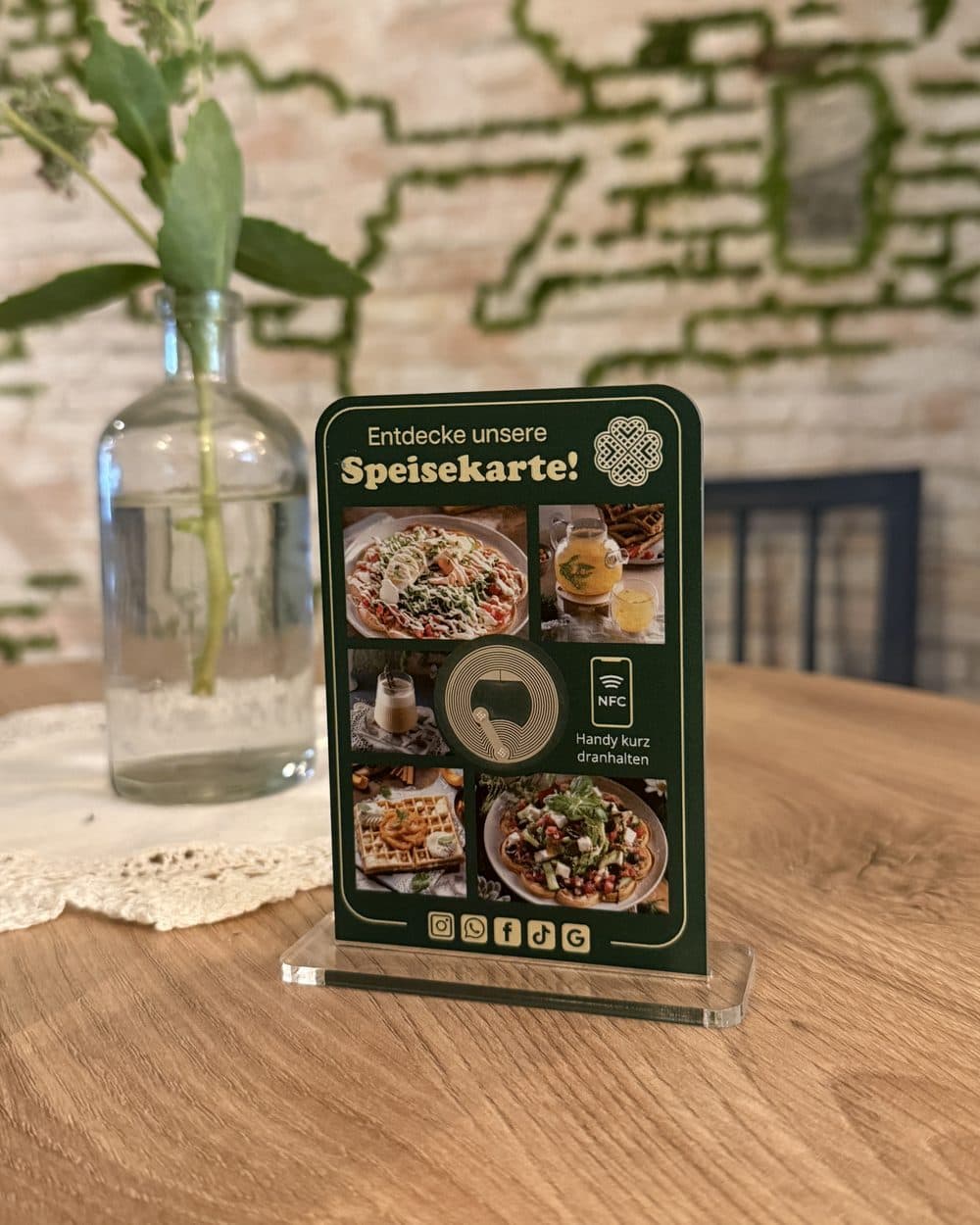 Der Aufsteller von Picknick Waffles and More auf einem Tisch im Café: „Entdecke unsere Speisekarte!“ mit Fotos der Waffeln, QR-Code und NFC